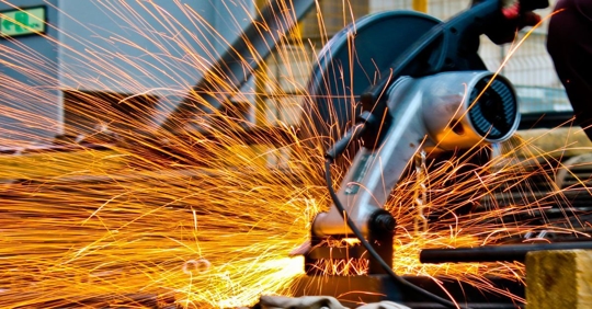 Man using a saw machine and sparks coming out of it.