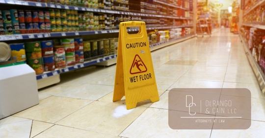 Yellow sign - caution. Wet floor is in the supermarket against the background of blurry products standing on the shelves